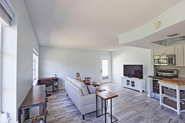 2950 SE Ocean Blvd Unit 127-8, Stuart, FL 34996 - living area with a textured ceiling, light wood finished floors, and baseboards