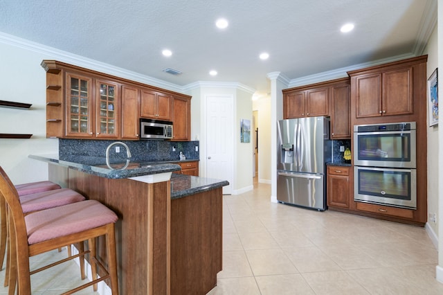 9413 Bristol Ridge Ct, West Palm Beach, FL 33411 - kitchen with appliances with stainless steel finishes, a peninsula, dark stone counters, a breakfast bar, and glass insert cabinets