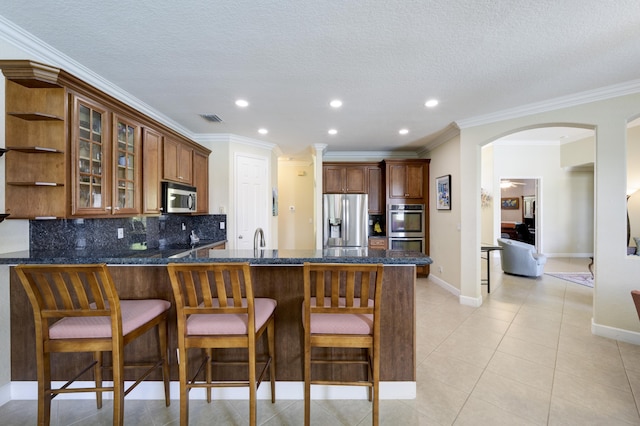 9413 Bristol Ridge Ct, West Palm Beach, FL 33411 - kitchen with appliances with stainless steel finishes, a peninsula, arched walkways, decorative backsplash, and glass insert cabinets