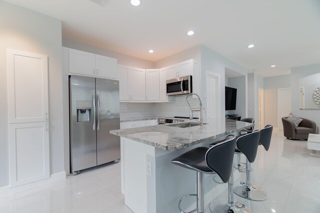 3185 Laurel Ridge Cir, Riviera Beach, FL 33404 - kitchen with stainless steel appliances, light stone countertops, light marble finish floors, a kitchen breakfast bar, and recessed lighting