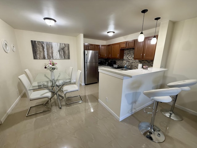 3280 NW 104th Ave Unit 3280, Coral Springs, FL 33065 - kitchen featuring freestanding refrigerator, a peninsula, a breakfast bar, decorative backsplash, and light countertops