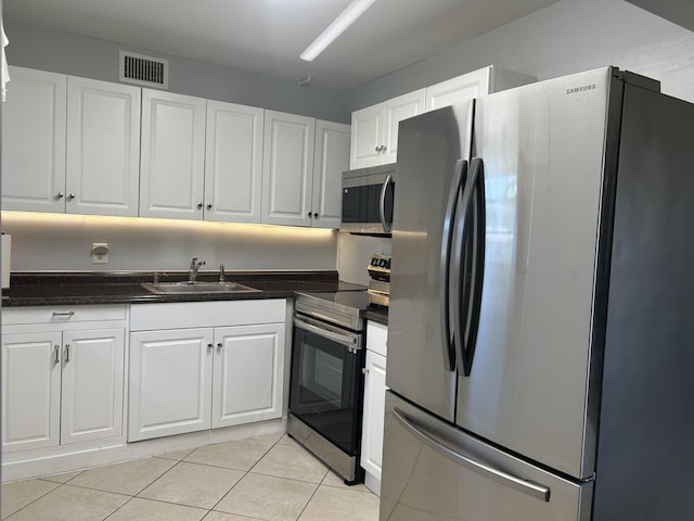 105 Sheffield E, West Palm Beach, FL 33417 - kitchen with stainless steel appliances, a sink, dark countertops, white cabinets, and light tile patterned flooring