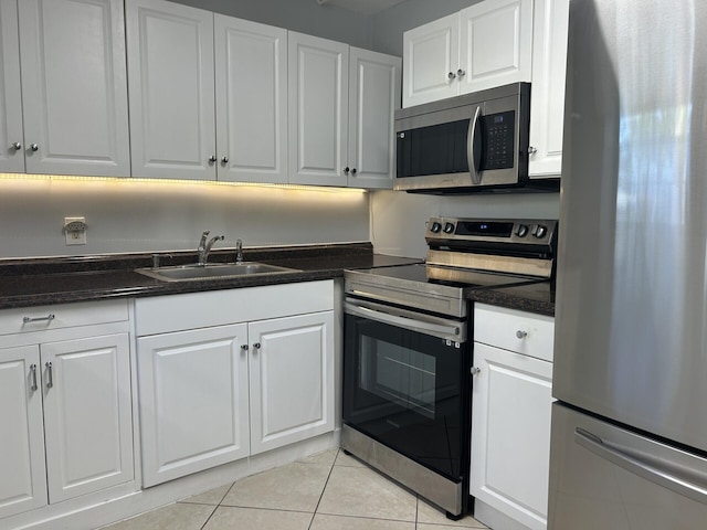 105 Sheffield E, West Palm Beach, FL 33417 - kitchen featuring appliances with stainless steel finishes, a sink, light tile patterned floors, and white cabinetry