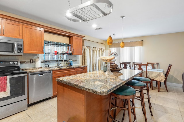 6815 Farragut Ln, Boynton Beach, FL 33437 - kitchen featuring appliances with stainless steel finishes, a sink, brown cabinetry, light tile patterned floors, and healthy amount of natural light