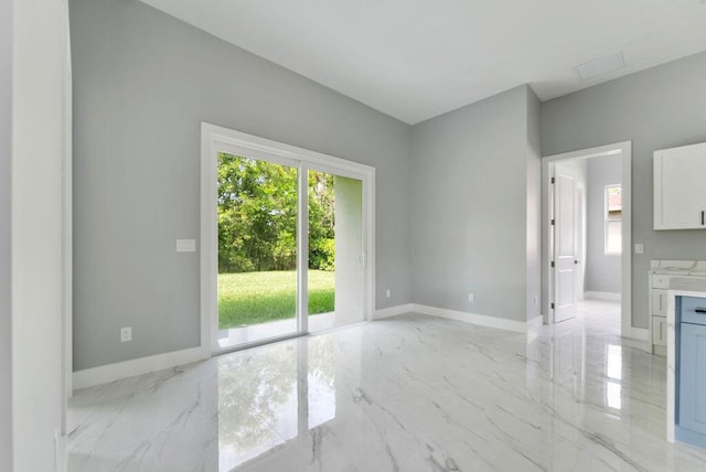 675 NE Moss Rose Pl, Port Saint Lucie, FL 34983 - empty room featuring plenty of natural light, light marble finish floors, and baseboards