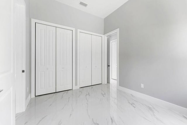 675 NE Moss Rose Pl, Port Saint Lucie, FL 34983 - unfurnished bedroom featuring two closets, marble finish flooring, and baseboards