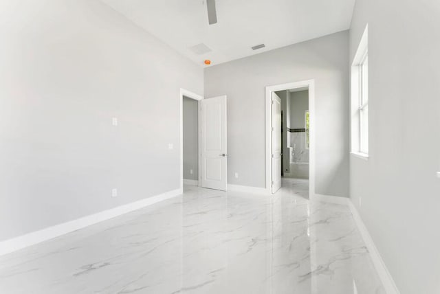 675 NE Moss Rose Pl, Port Saint Lucie, FL 34983 - unfurnished bedroom featuring light marble finish flooring, baseboards, ensuite bathroom, and ceiling fan