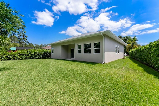 675 NE Moss Rose Pl, Port Saint Lucie, FL 34983 - rear view of house featuring stucco siding and a yard