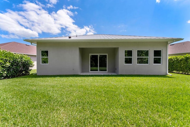 675 NE Moss Rose Pl, Port Saint Lucie, FL 34983 - back of property with stucco siding, a lawn, a standing seam roof, and metal roof