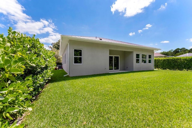 675 NE Moss Rose Pl, Port Saint Lucie, FL 34983 - rear view of house featuring stucco siding, a lawn, metal roof, and a standing seam roof