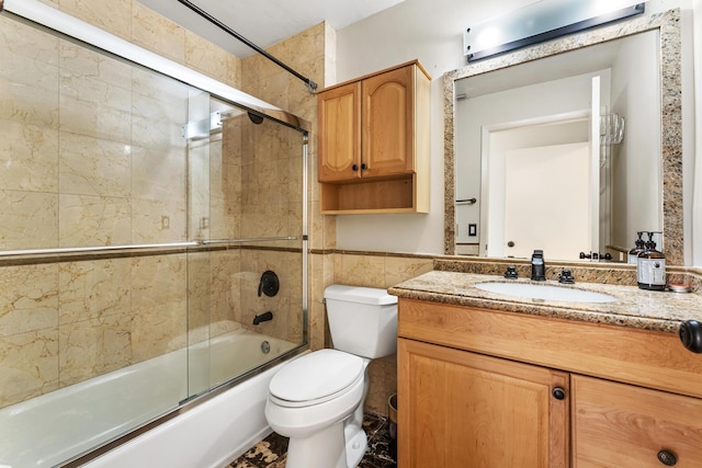 2561 Carambola Cir N Unit 1848Bldg 8, Coconut Creek, FL 33066 - bathroom with combined bath / shower with glass door, toilet, vanity, tile walls, and wainscoting