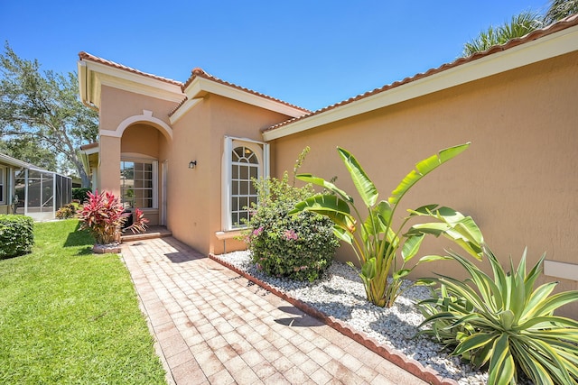 doorway to property with stucco siding, a yard, and a tile roof