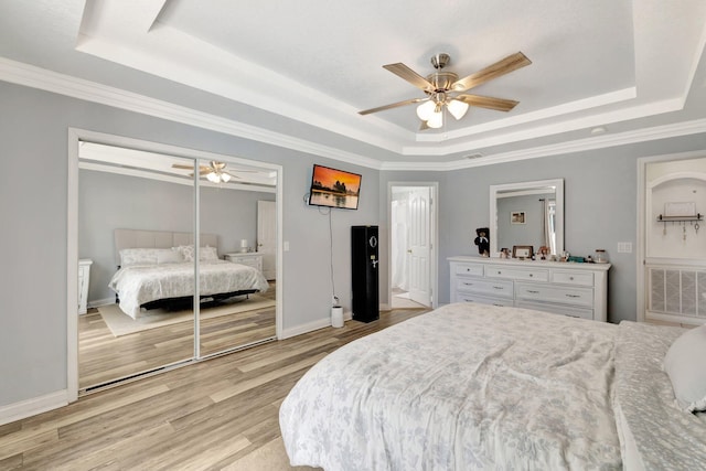 401 SE Ron Rico Ter, Port Saint Lucie, FL 34983 - bedroom featuring a raised ceiling, light wood-style floors, baseboards, a ceiling fan, and a closet