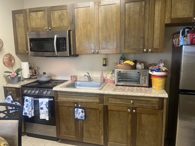 702 48th St, West Palm Beach, FL 33407 - kitchen with stainless steel appliances, a sink, light countertops, and light tile patterned floors