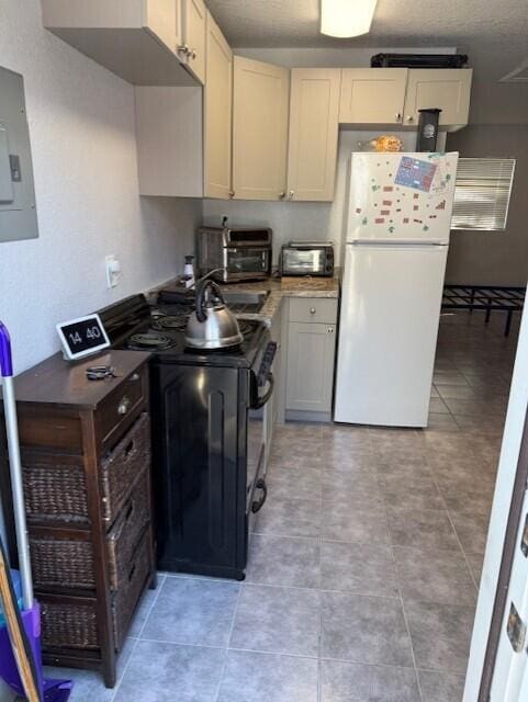 kitchen featuring freestanding refrigerator, black range with electric cooktop, electric panel, light tile patterned floors, and a textured ceiling