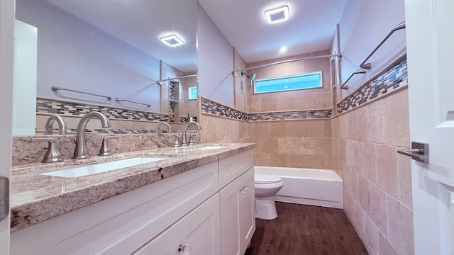 1942 Windsor Dr, North Palm Beach, FL 33408 - bathroom with tile walls, toilet, double vanity, wood finished floors, and shower / bathtub combination