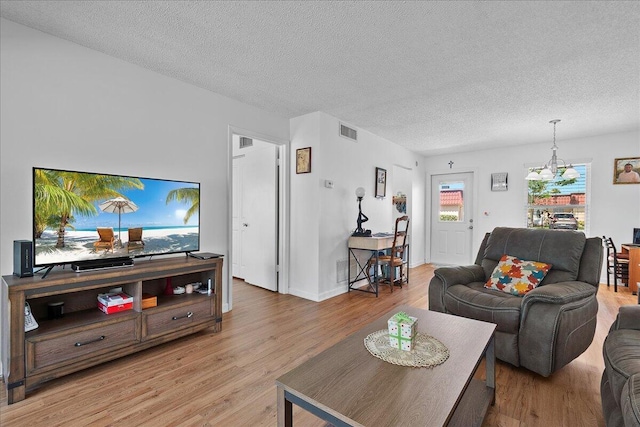 884 Worcester Ln, Lake Worth, FL 33467 - living room with light wood-style flooring, a textured ceiling, baseboards, and a chandelier