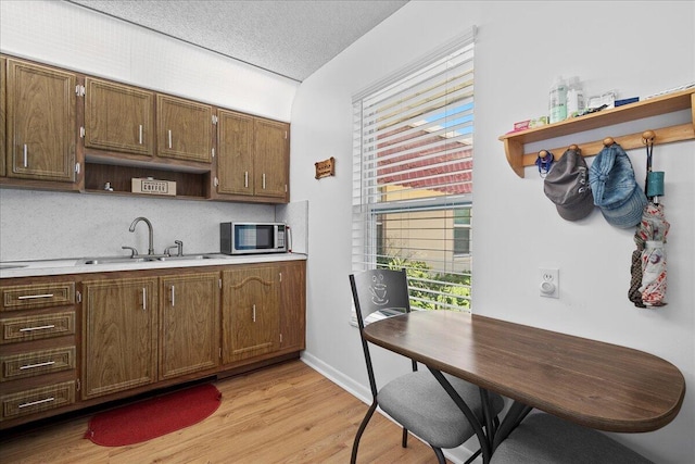 884 Worcester Ln, Lake Worth, FL 33467 - kitchen with open shelves, stainless steel microwave, light countertops, a sink, and light wood finished floors