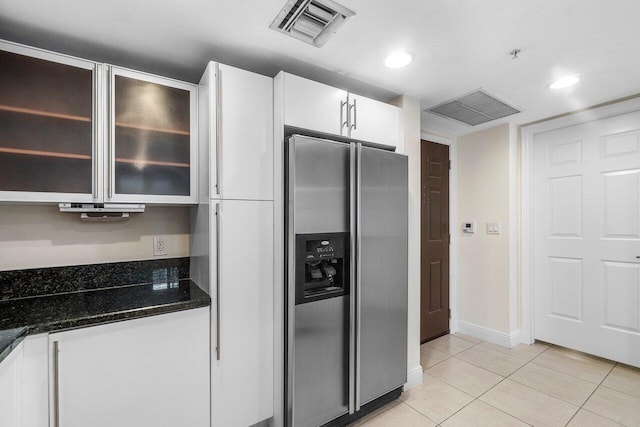 610 Clematis St Unit 236, West Palm Beach, FL 33401 - kitchen featuring stainless steel fridge, white cabinets, light tile patterned floors, dark stone countertops, and glass insert cabinets
