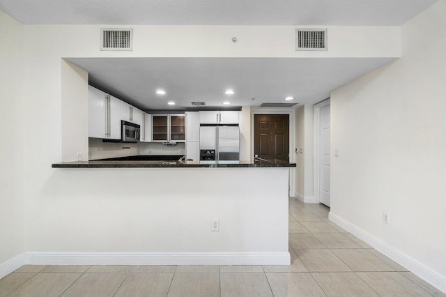 610 Clematis St Unit 236, West Palm Beach, FL 33401 - kitchen featuring appliances with stainless steel finishes, glass insert cabinets, a peninsula, dark countertops, and baseboards