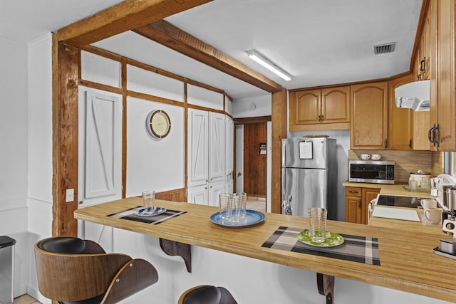 14601 Orange Ave, Fort Pierce, FL 34945 - kitchen with appliances with stainless steel finishes, extractor fan, a breakfast bar, brown cabinets, and a peninsula