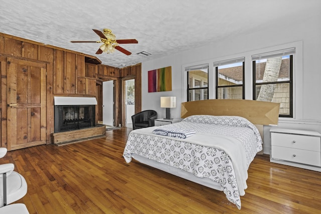 14601 Orange Ave, Fort Pierce, FL 34945 - bedroom featuring hardwood / wood-style floors, a fireplace with raised hearth, access to outside, a textured ceiling, and wooden walls