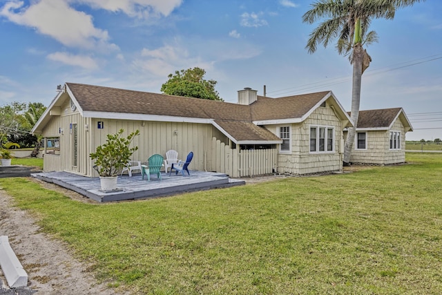14601 Orange Ave, Fort Pierce, FL 34945 - rear view of property featuring a deck, roof with shingles, a yard, and a chimney