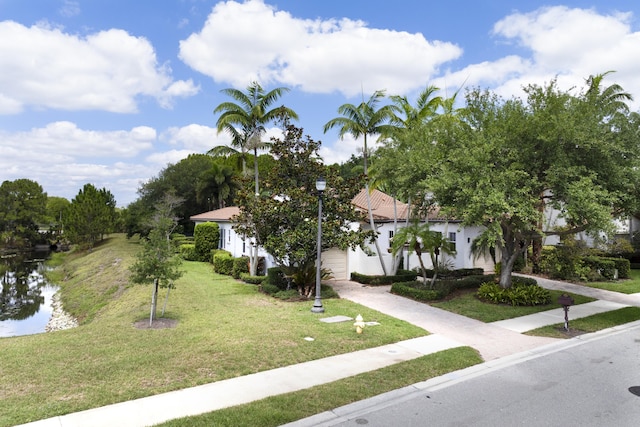 1081 Vintner Blvd, Palm Beach Gardens, FL 33410 - view of property hidden behind natural elements featuring concrete driveway, a front yard, a water view, and a garage