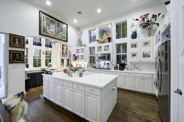 1081 Vintner Blvd, Palm Beach Gardens, FL 33410 - kitchen with appliances with stainless steel finishes, ornamental molding, white cabinets, light countertops, and a center island