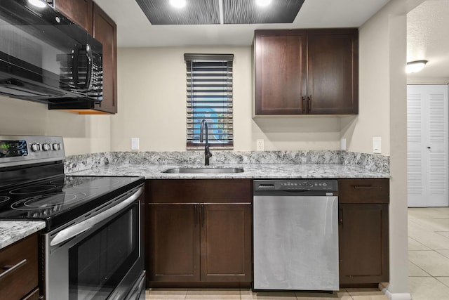 1631 SE Green Acres Cir Unit Bb103, Port Saint Lucie, FL 34952 - kitchen with stainless steel appliances, a sink, light tile patterned floors, and dark brown cabinetry