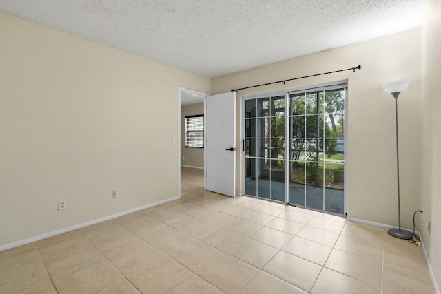 1631 SE Green Acres Cir Unit Bb103, Port Saint Lucie, FL 34952 - empty room featuring light tile patterned floors, a textured ceiling, and baseboards