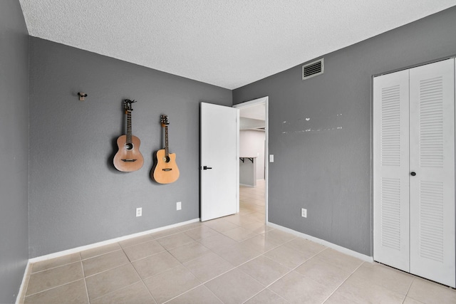 1631 SE Green Acres Cir Unit Bb103, Port Saint Lucie, FL 34952 - unfurnished bedroom featuring tile patterned flooring, a textured ceiling, baseboards, and a closet