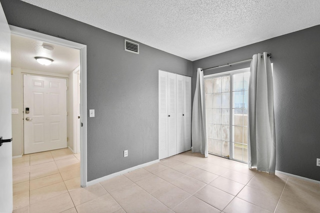 1631 SE Green Acres Cir Unit Bb103, Port Saint Lucie, FL 34952 - unfurnished bedroom with light tile patterned floors, baseboards, a textured ceiling, and a closet