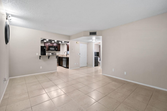 1631 SE Green Acres Cir Unit Bb103, Port Saint Lucie, FL 34952 - unfurnished living room featuring light tile patterned floors, baseboards, a sink, and a textured ceiling