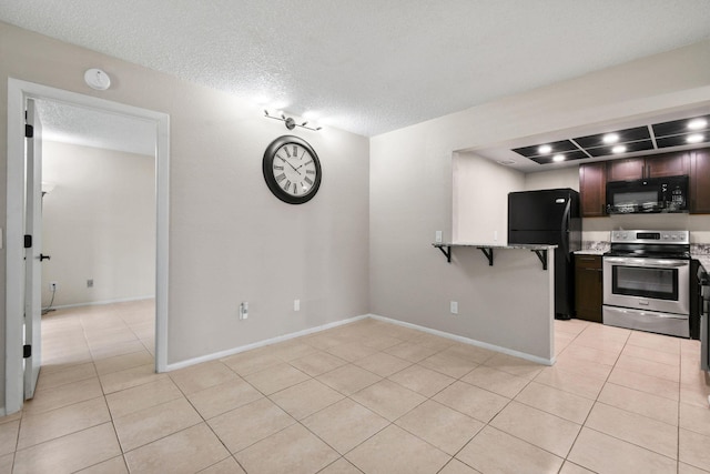 1631 SE Green Acres Cir Unit Bb103, Port Saint Lucie, FL 34952 - kitchen with black appliances, light tile patterned flooring, a textured ceiling, a breakfast bar, and dark brown cabinets
