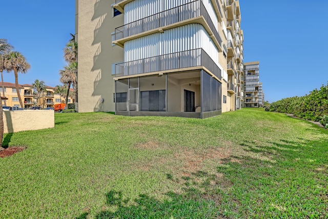 7430 S Ocean Dr Unit 319, Jensen Beach, FL 34957 - rear view of house featuring a balcony, a yard, a sunroom, and stucco siding