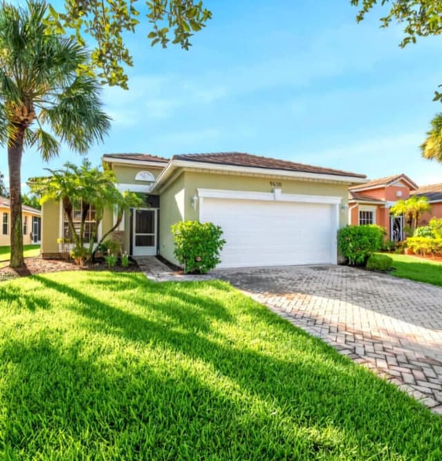 9658 SW Lindale Trace Blvd, Port Saint Lucie, FL 34987 - view of front of house with stucco siding, an attached garage, a front yard, and driveway