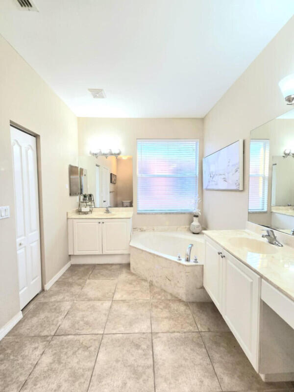 9658 SW Lindale Trace Blvd, Port Saint Lucie, FL 34987 - bathroom with plenty of natural light, two vanities, a garden tub, and tile patterned floors