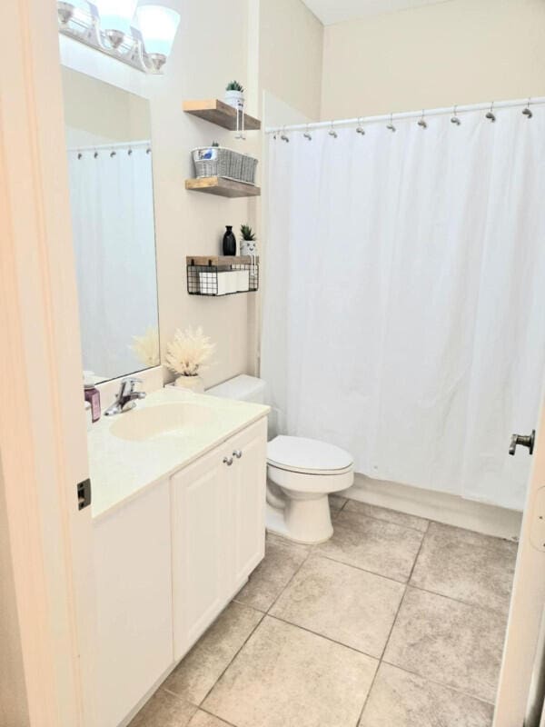 9658 SW Lindale Trace Blvd, Port Saint Lucie, FL 34987 - full bathroom with toilet, tile patterned floors, vanity, and a shower with shower curtain