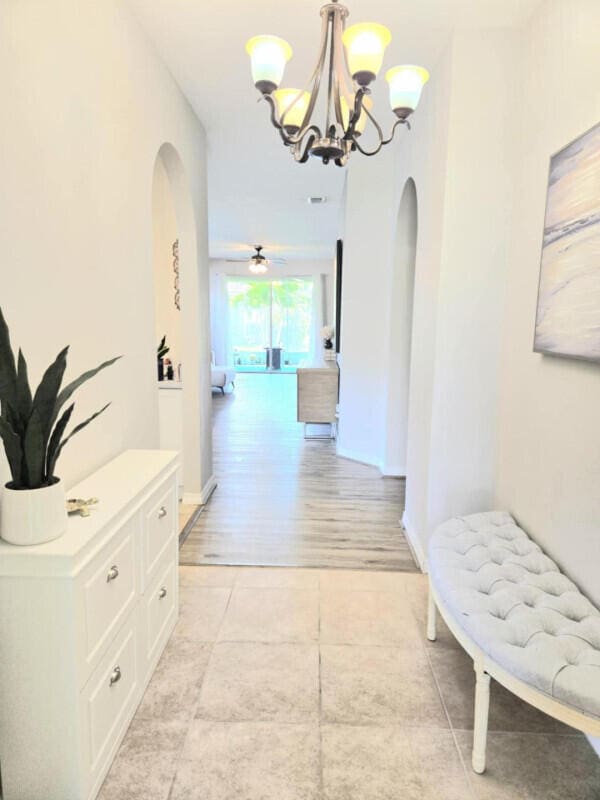 9658 SW Lindale Trace Blvd, Port Saint Lucie, FL 34987 - hall featuring arched walkways, a chandelier, and light tile patterned floors