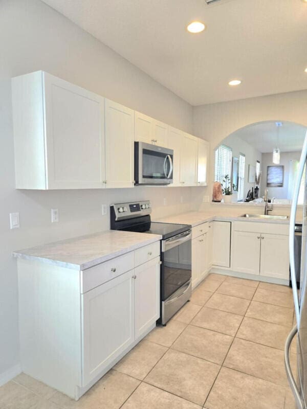 9658 SW Lindale Trace Blvd, Port Saint Lucie, FL 34987 - kitchen featuring stainless steel appliances, a sink, white cabinetry, and recessed lighting