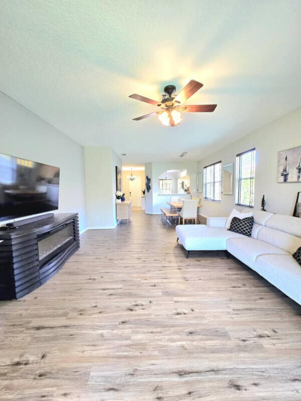 9658 SW Lindale Trace Blvd, Port Saint Lucie, FL 34987 - living area featuring wood finished floors, ceiling fan, and a glass covered fireplace