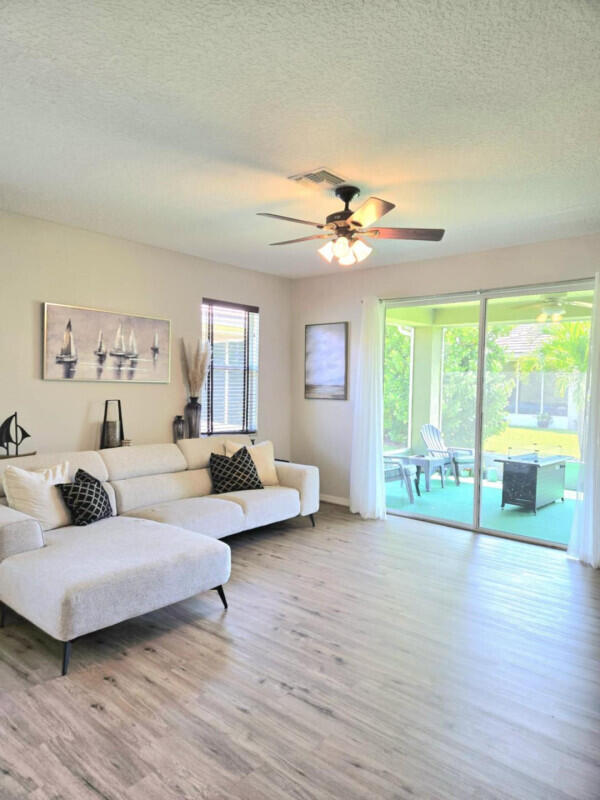 9658 SW Lindale Trace Blvd, Port Saint Lucie, FL 34987 - living area featuring a textured ceiling, wood finished floors, ceiling fan, and baseboards