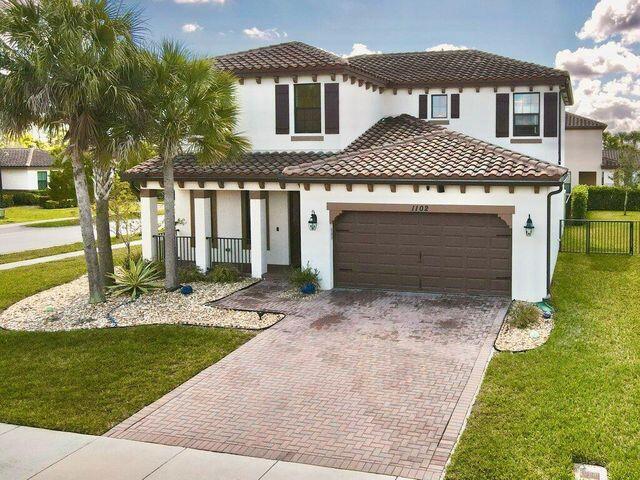1102 Brinely Pl, Royal Palm Beach, FL 33411 - mediterranean / spanish home with decorative driveway, stucco siding, an attached garage, and a tiled roof