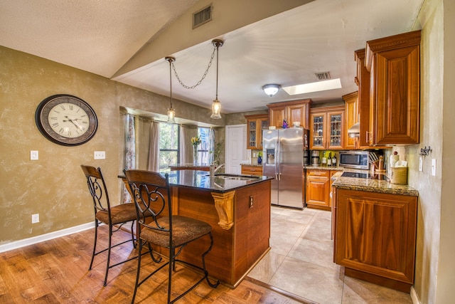11033 67th Pl N, The Acreage, FL 33412 - kitchen with appliances with stainless steel finishes, brown cabinets, a sink, a breakfast bar area, and lofted ceiling