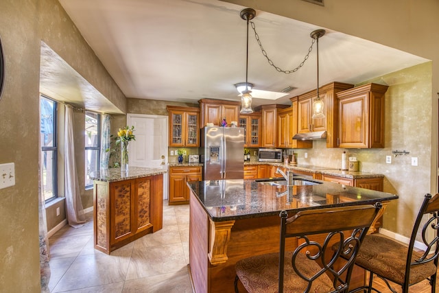 11033 67th Pl N, The Acreage, FL 33412 - kitchen featuring appliances with stainless steel finishes, a kitchen island with sink, a sink, brown cabinetry, and under cabinet range hood