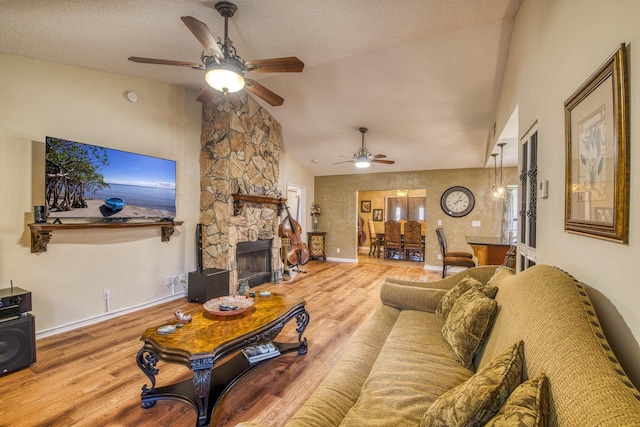 11033 67th Pl N, The Acreage, FL 33412 - living area featuring a ceiling fan, vaulted ceiling, wood finished floors, a stone fireplace, and baseboards