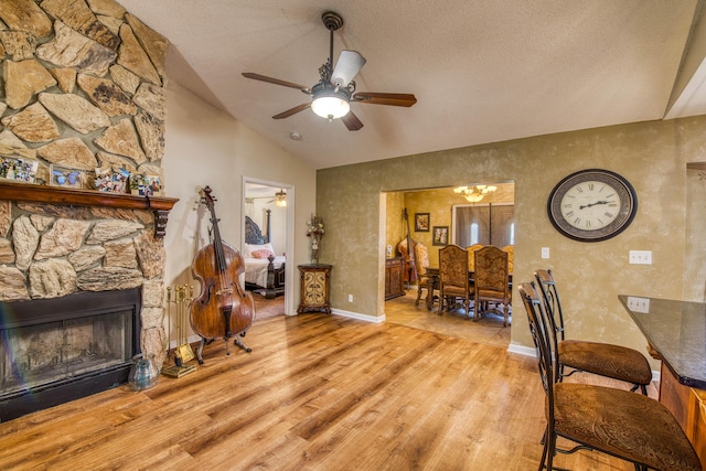 11033 67th Pl N, The Acreage, FL 33412 - living room with vaulted ceiling, a ceiling fan, wood finished floors, a stone fireplace, and baseboards