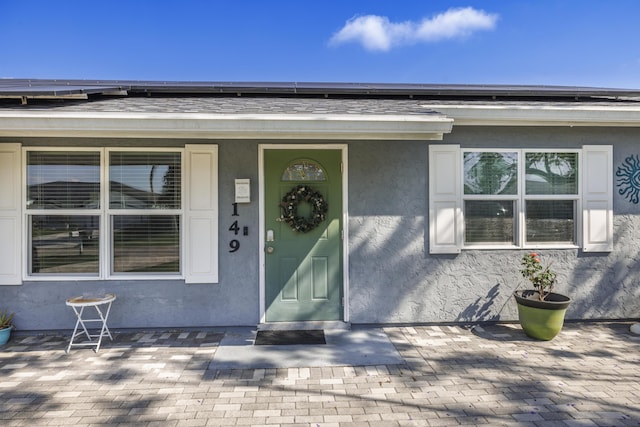 149 SW Grimaldo Ter, Port Saint Lucie, FL 34984 - view of exterior entry featuring stucco siding, covered porch, and solar panels