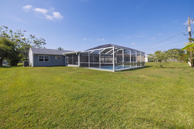 149 SW Grimaldo Ter, Port Saint Lucie, FL 34984 - back of house featuring a lawn, cooling unit, glass enclosure, an outdoor pool, and stucco siding